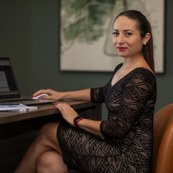 Confident businesswoman in stylish dress working on a laptop at her desk.